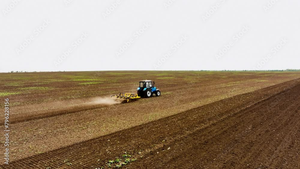 A tractor cultivator cultivates and digs the soil. A tractor plows a field during daylight in the spring. Agricultural food production. Industry concept. A tractor cultivator cultivates and digs the soil. A tractor plows a field during daylight in the spring. Agricultural food production. Industry concept.