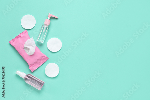 Bottles of sanitizer with wet tissues pack and cotton pads on turquoise background