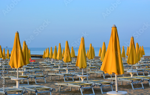the beach  umbrellas still closed in the early morning in front of the sea