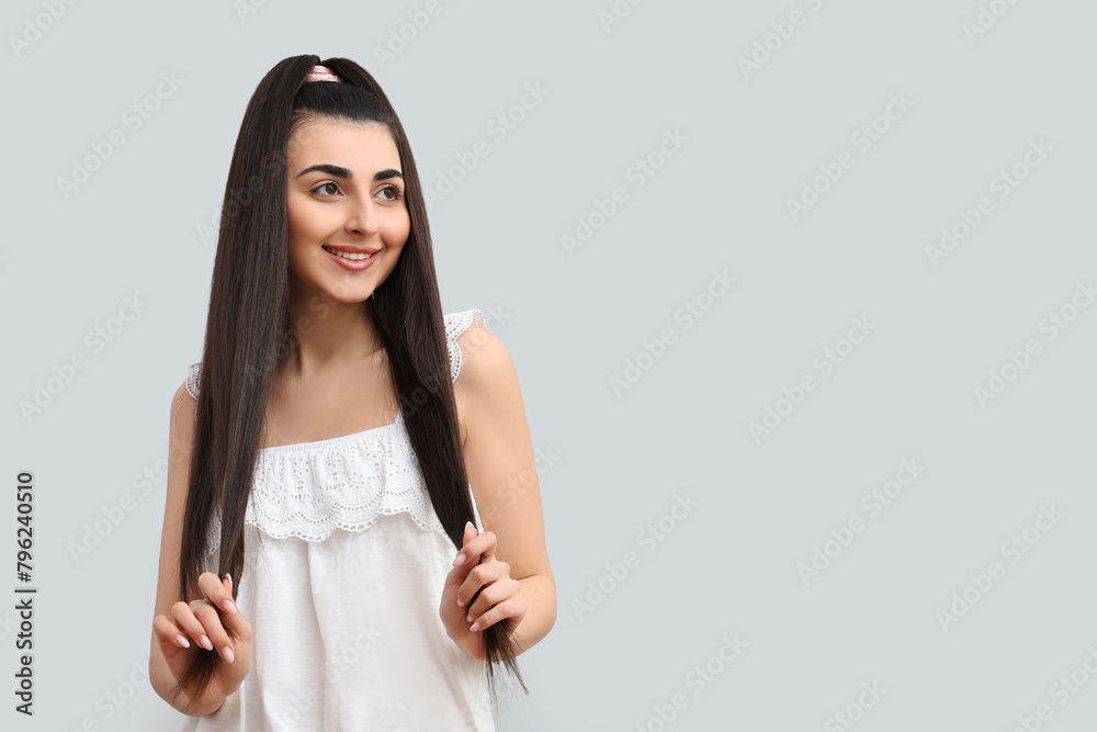 Beautiful young happy woman with stylish ponytail hairstyle on grey background Beautiful young happy woman with stylish ponytail hairstyle on grey background
