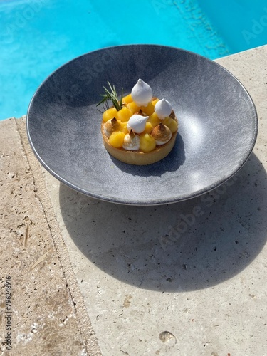gourmet lemon meringue pie on a plate beside a swimming pool 