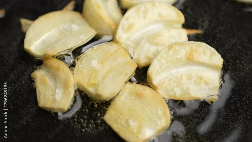 Frying garlic in oil in pan, close up Frying garlic in oil in pan, close up
