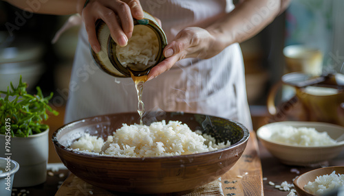 Woman adding vinegar into boiled rice on wooden table