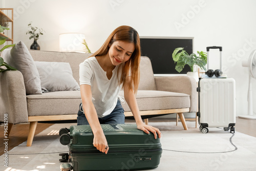 A young Asian tourist carefully packs her suitcase in preparation for a weekend away.