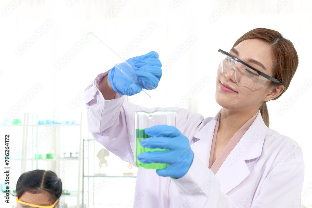 Fototapeta premium Portrait of happy beautiful Asian scientist woman in lab coats with safety glasses do science experiments. Researcher pour chemical from tube into beaker for research, female work in science field.