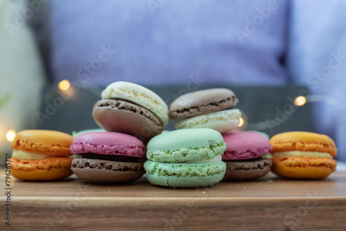 Close up delicious macaroon cookies in fresh mint green vanilla beige chocolate brown orange and pink colors. Dark gray background, wooden textured table. Contrast bright combination, bakery culinary.