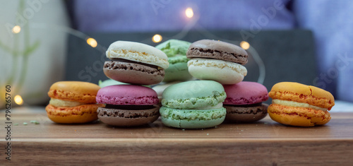 Close up delicious macaroon cookies in fresh mint green vanilla beige chocolate brown orange and pink colors. Dark background, wooden table, widescreen. Contrast bright combination, bakery culinary.