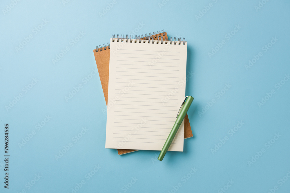 Top view of notebook and fountain pen on blue background Top view of notebook and fountain pen on blue background