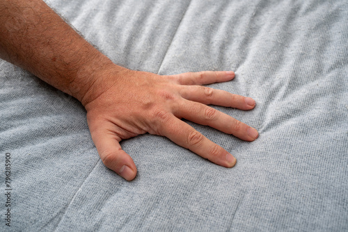 The man checks the quality and softness of the new mattress he will buy by pressing it with his hand