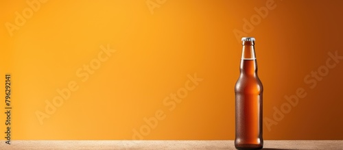 Bottle of beer on table with orange backdrop photo
