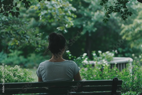 A young woman enjoys a moment of solitude sitting alone on a park bench surrounded by greenery