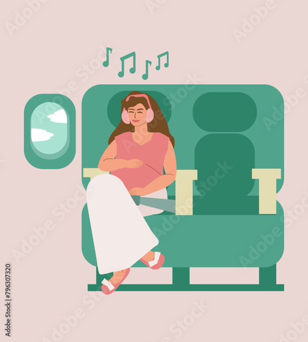 A young pregnant woman sits in a seat on an airplane, smiles, listens to music on headphones alone and looks out the window. Relaxation, meditation, maternity leave, motherhood, the expectant mother 