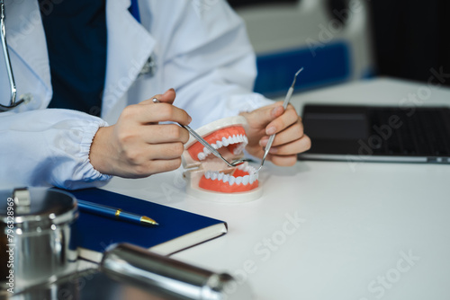 Dentist working tooth model at office in the morning at the desk dentistry and recommend patient at workplace concept.