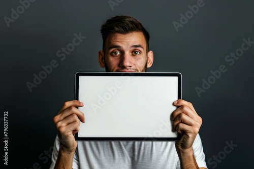 Digital mockup caucasian man in his 20s holding a tablet with a fully white screen