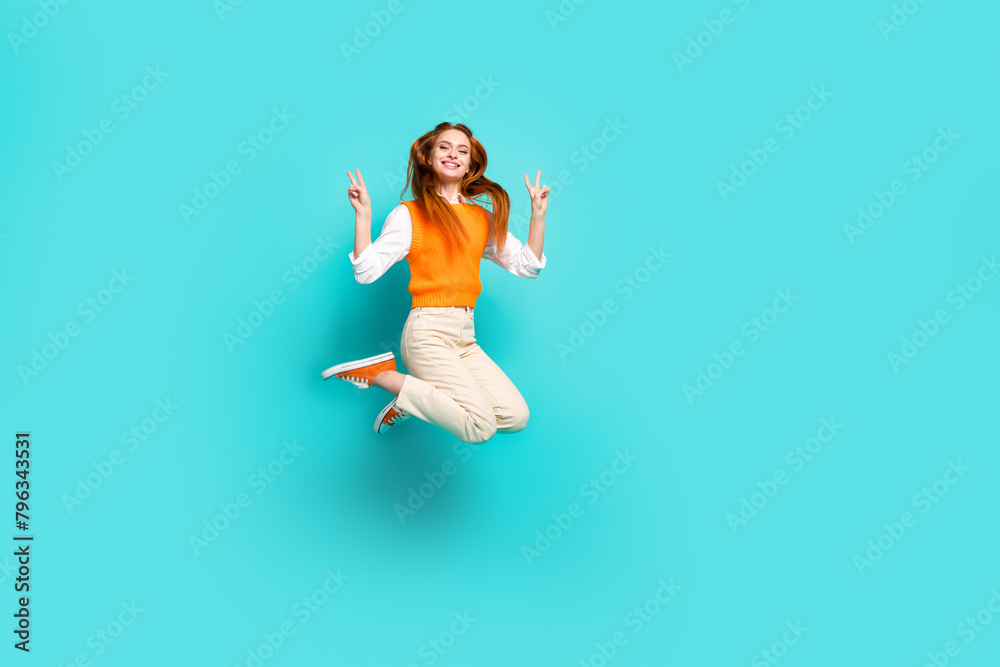 Photo of cheerful lovely funny girl wear orange trendy clothes jump up hands v-sign isolated on aquamarine color background Photo of cheerful lovely funny girl wear orange trendy clothes jump up hands v-sign isolated on aquamarine color background