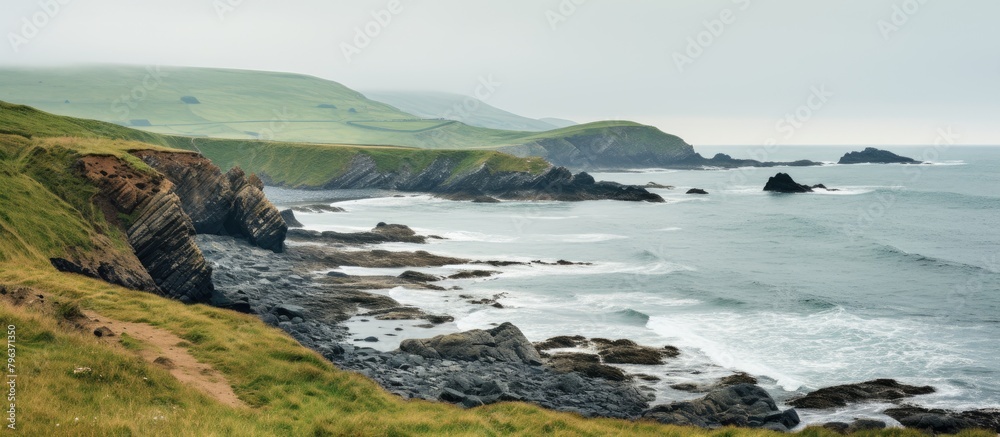 Rocky coast and green hill in background
