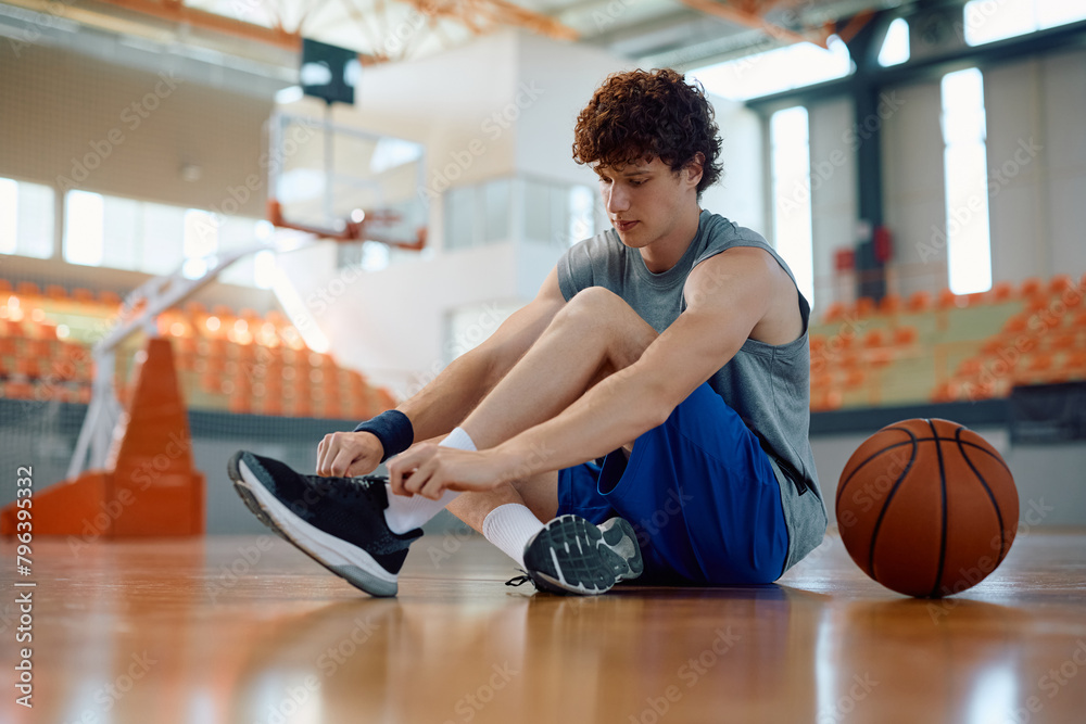 Young basketball player tying shoelace on court. Young basketball player tying shoelace on court.