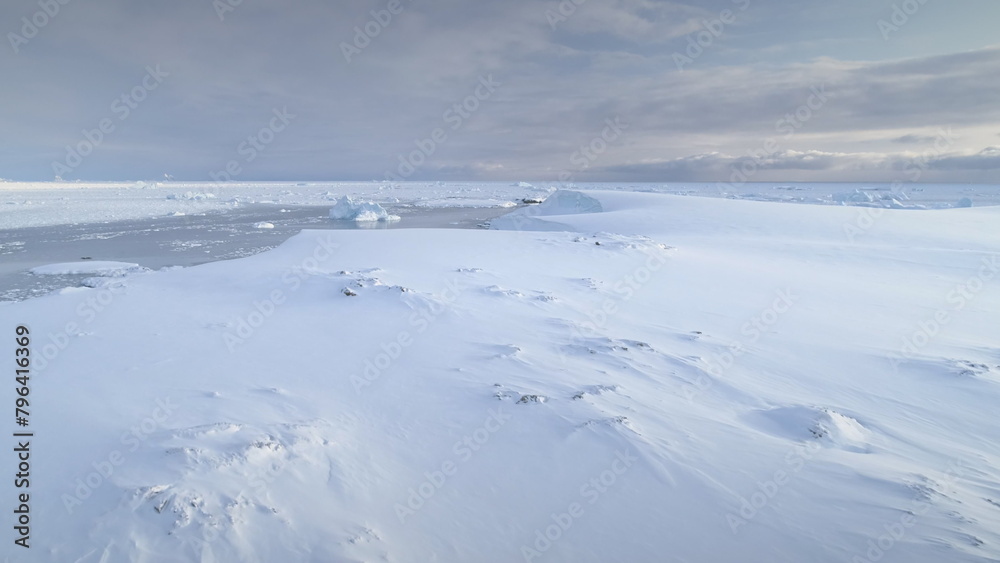 Infinitely, endless polar snowy desert in Antarctica. Frozen iceberg. South Pole frost surface. Scientific base. Snow covered mountains on horizon. Aerial view flight. Ice Landscape. Winter frozen