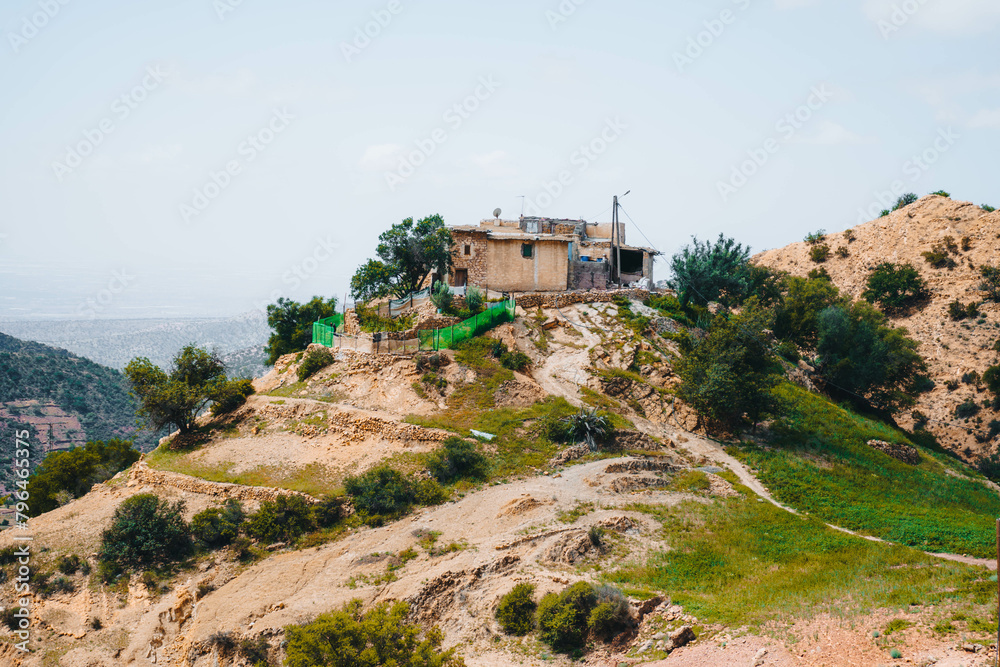 A building on a hill, overlooking the sky, trees, and mountains in Morocco
