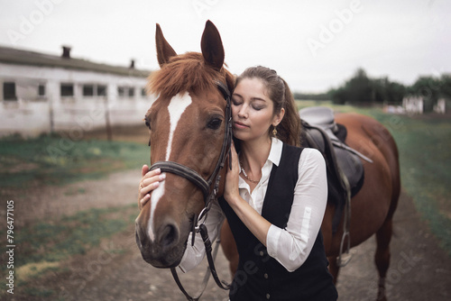 A beautiful woman in jockey clothes and a brown horse