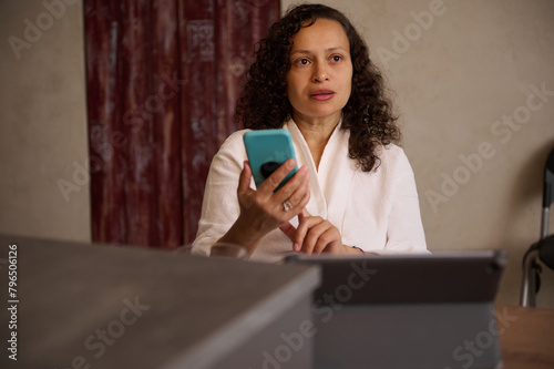 Young pretty woman using mobile phone, sitting at table at home.
