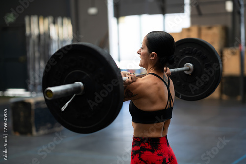 Strong mature woman lifting weights in a gym