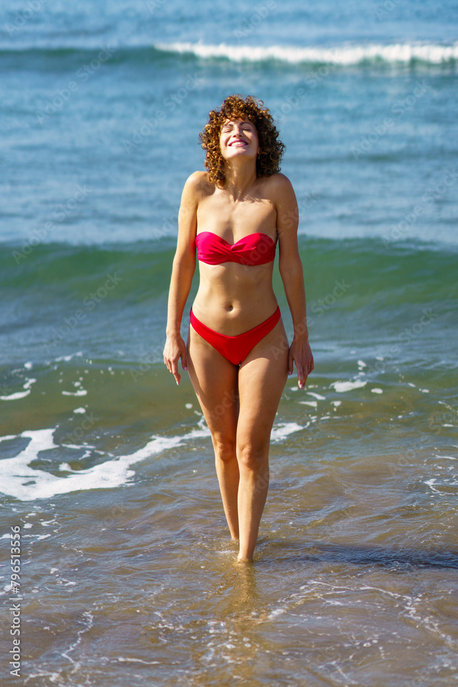 Slim woman in bikini walking in ocean water Slim woman in bikini walking in ocean water