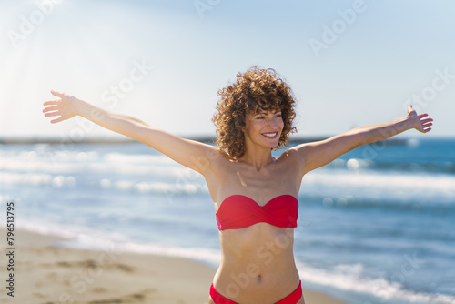 Happy woman with ginger hair standing in bikini on beach