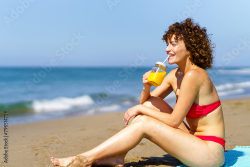 Happy woman enjoying drink on beach