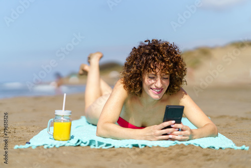 Happy woman with smartphone and juice on beach
