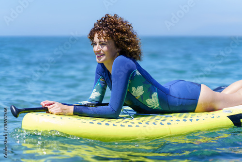 Happy lady resting on paddleboard in ocean