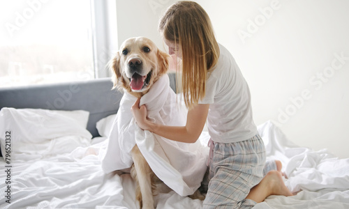 Joyful Young Girl Having Fun With Her Golden Retriever Pet While Wrapped In A Blanket