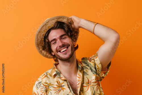 A cheerful man in summer attire happily tipping his hat in greeting against an orange backdrop. This image captures the joy of a sunny vacation moment. photo
