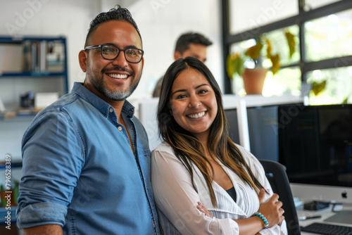 Two cheerful Latino business individuals working together in a dynamic office atmosphere.