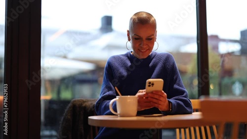  woman in cafe writing a text message with phone laughing. 