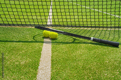  A yellow tennis ball and tennis racket lies on the clay court.