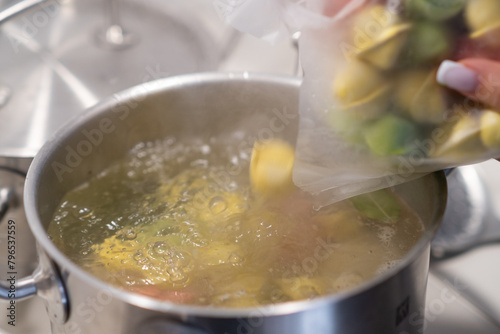 In a pot, colorful dumplings are being boiled. Preparing lunch or dinner for children and family.