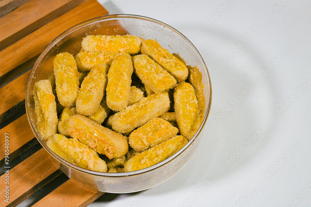Long cheese and nut cookies are served in round packaging with a plain white background and on a wooden coaster Long cheese and nut cookies are served in round packaging with a plain white background and on a wooden coaster