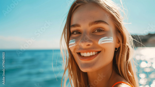 Lächelnde blonde Frau mit Sonnencreme auf der Wange am Strand photo