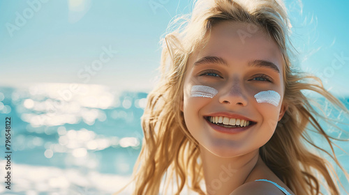 Lächelnde blonde Frau mit Sonnencreme auf der Wange am Strand © Michael Anger