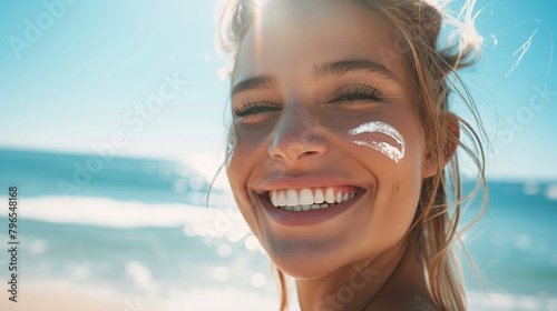 Lächelnde blonde Frau mit Sonnencreme auf der Wange am Strand photo