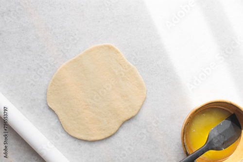 Coco bread dough rising on a parchment lined baking tray, shaped coco bread about to be baked, process of making jamaican coco bread