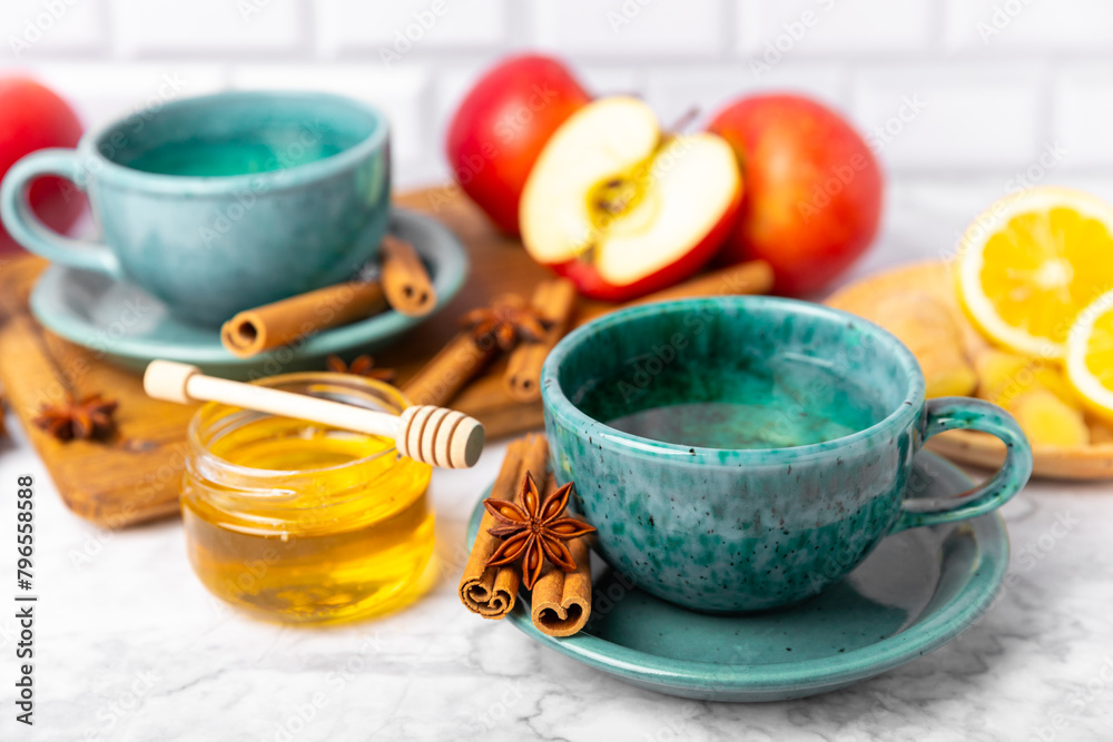 Fragrant hot tea with cinnamon stick and anise on a textured wooden background. A cup of hot tea with honey, lemon, mint and apples. Spicy tea with spices. Immunity tea. Health concept.Copy space. Fragrant hot tea with cinnamon stick and anise on a textured wooden background. A cup of hot tea with honey, lemon, mint and apples. Spicy tea with spices. Immunity tea. Health concept.Copy space.