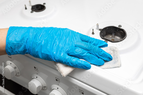 housewife in rubber gloves wipes gas stove.