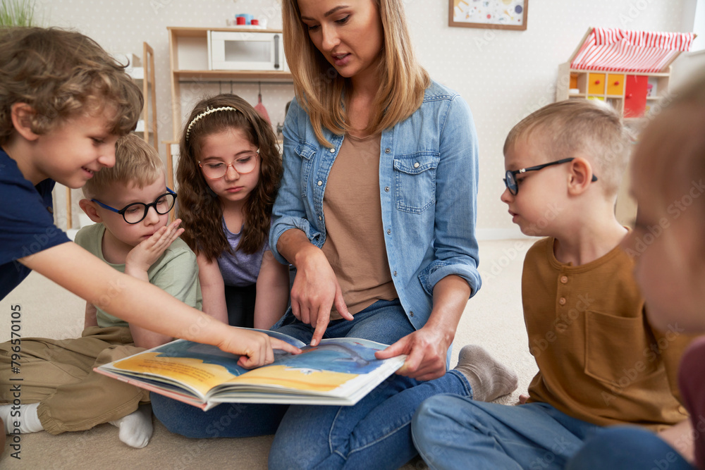 Fototapeta premium Teacher and pupils reading book together
