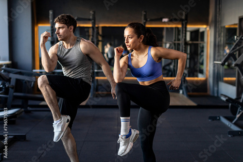 Active couple doing elbow-knee warm up exercises during fitness workout in modern gym