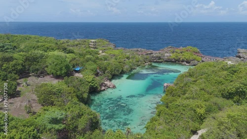 Weekuri Lagoon, Sumba island, Indonesia. A beautiful blue lake with a green forest in the background. The water is calm and clear, and the trees are lush and green photo
