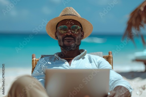 A man in casual beachwear works on his laptop by the sea, symbolizing remote work or a mobile office photo