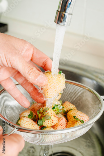 man rinsing some white strawberries © nito