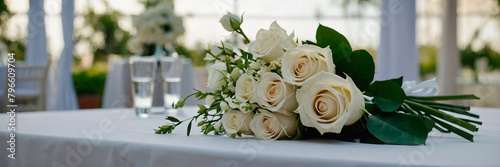 White bouquet with white roses on a wedding table decorated with white tablecloth